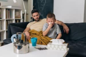 a father sitting near his ill son who is suffering from seasonal flu