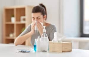 A girl suffering with Seasonal Allergy Sinus Infection cleaning her nose with a tissue
