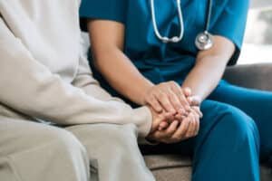 A male doctor in scrub holding hands of his patient supporting Mental Health