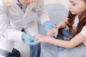 A doctor wearing lab coat and analyzing Skin disorders of a young girl