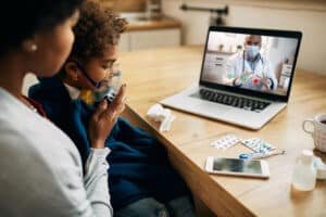 A mom nebulising her child while talking to a doctor on a video call on a laptop